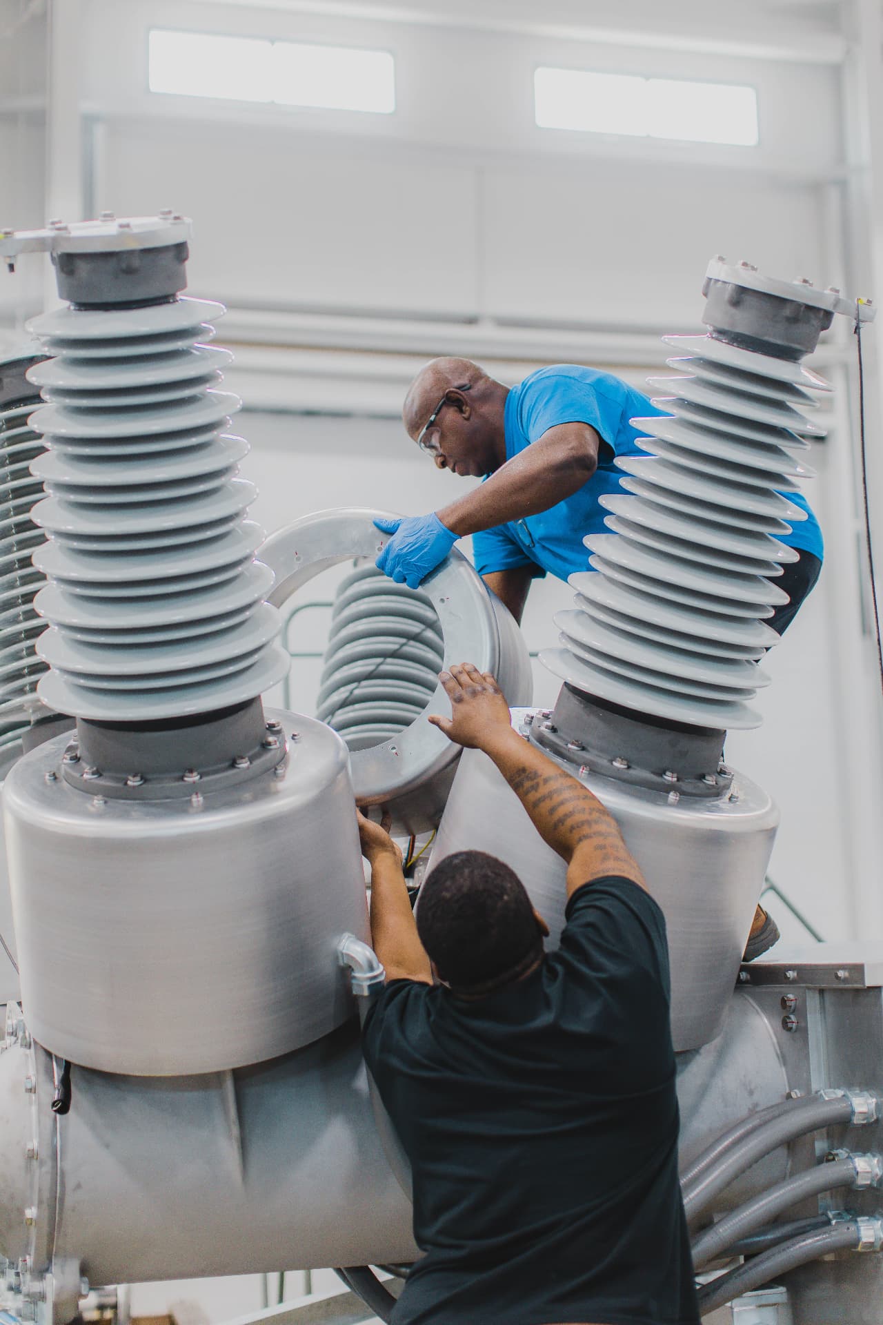Two Meiden America Switchgear technicians assembling a high-voltage circuit breaker